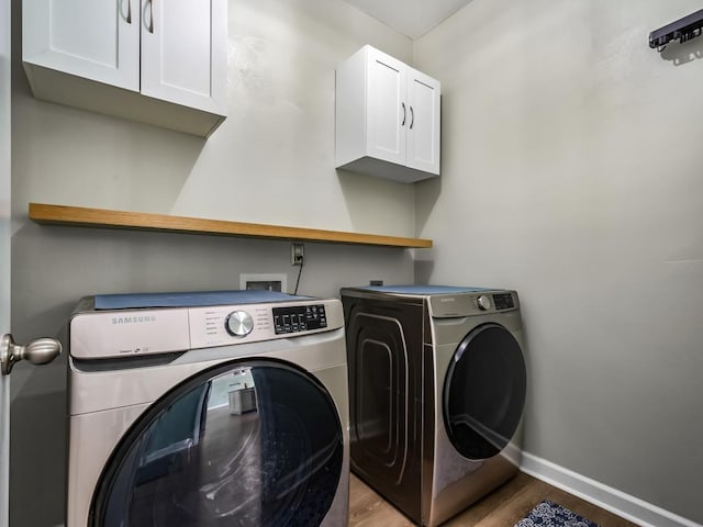 washroom with cabinets, wood-type flooring, and independent washer and dryer