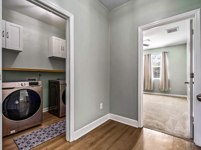 washroom featuring separate washer and dryer, hardwood / wood-style flooring, and cabinets