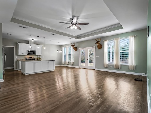 unfurnished living room featuring ceiling fan, dark hardwood / wood-style floors, and a raised ceiling