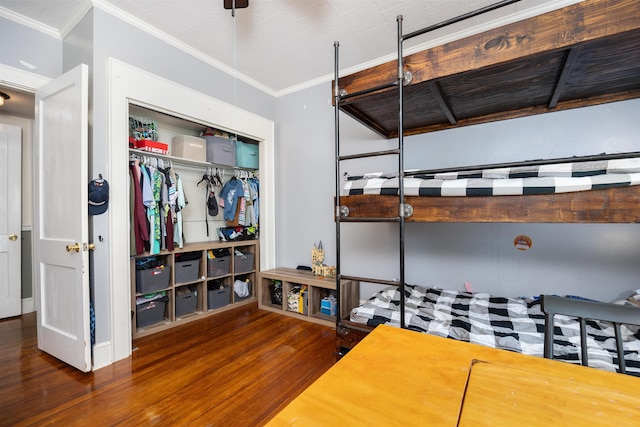 bedroom with dark wood-type flooring, ornamental molding, and a closet