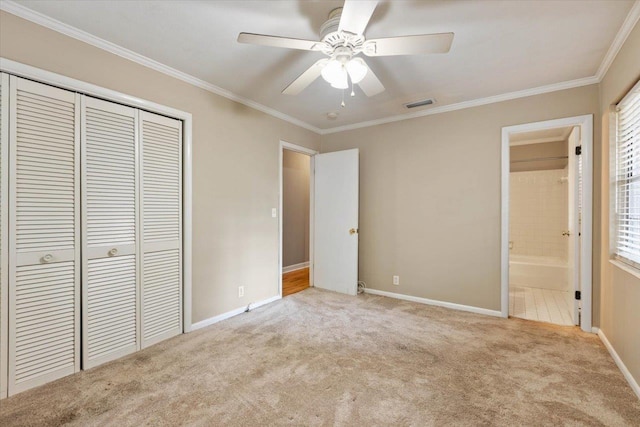 unfurnished bedroom with ensuite bathroom, crown molding, light colored carpet, a closet, and ceiling fan