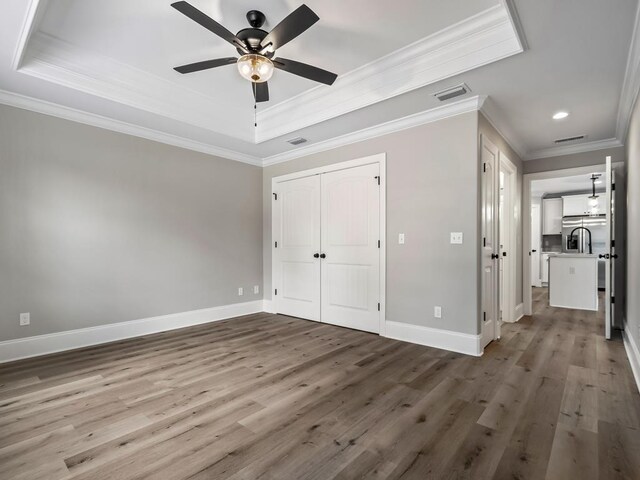 70 Beeler Rd, Crawfordville, FL 32327 - unfurnished bedroom with ornamental molding, a tray ceiling, wood finished floors, recessed lighting, and stainless steel fridge with ice dispenser