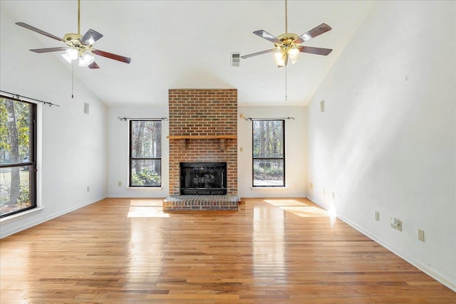 unfurnished living room featuring a fireplace, ceiling fan, light wood-type flooring, and high vaulted ceiling