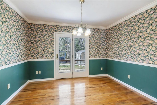 unfurnished dining area featuring hardwood / wood-style flooring, ornamental molding, and an inviting chandelier