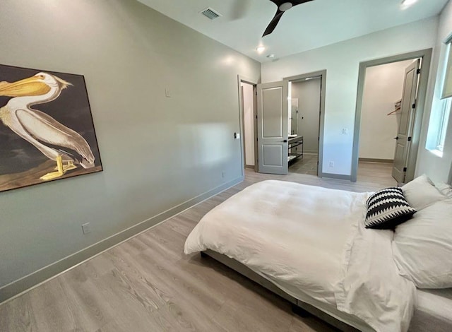 bedroom featuring ensuite bathroom, visible vents, light wood-style floors, and baseboards