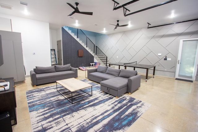 living room with stairway, an accent wall, a ceiling fan, and visible vents