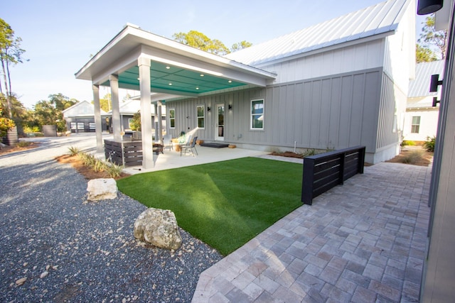 back of property with metal roof, a patio area, and a yard