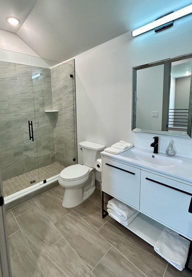 bathroom featuring vaulted ceiling, vanity, toilet, and a shower stall