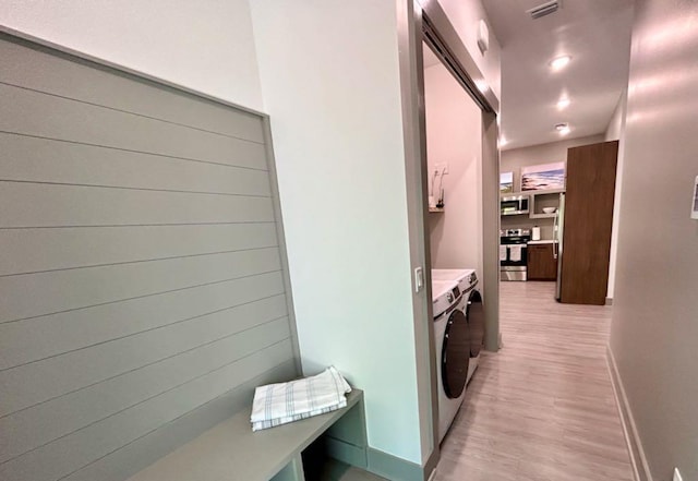 laundry area with washer and clothes dryer, cabinet space, baseboards, visible vents, and light wood-style floors