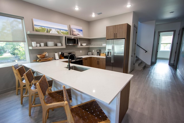 kitchen featuring appliances with stainless steel finishes, a peninsula, light countertops, and a kitchen bar