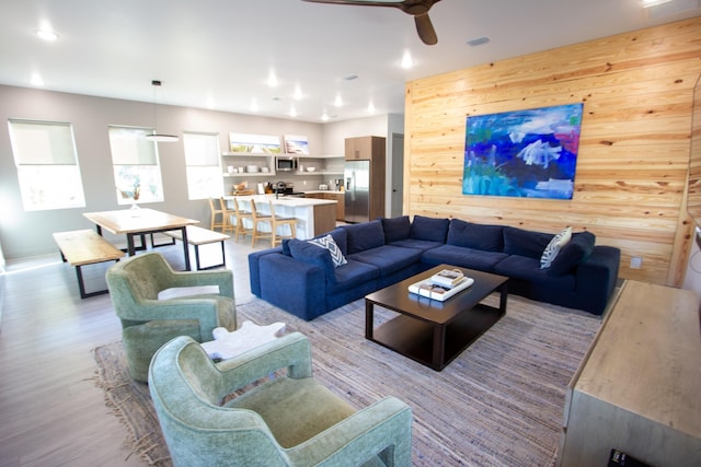 living area featuring recessed lighting, ceiling fan, light wood-style floors, and wood walls