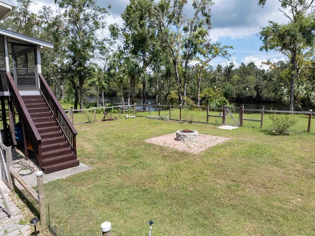 view of yard with a sunroom, an outdoor fire pit, and a water view