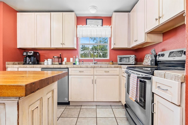 kitchen with light tile patterned flooring, sink, and appliances with stainless steel finishes