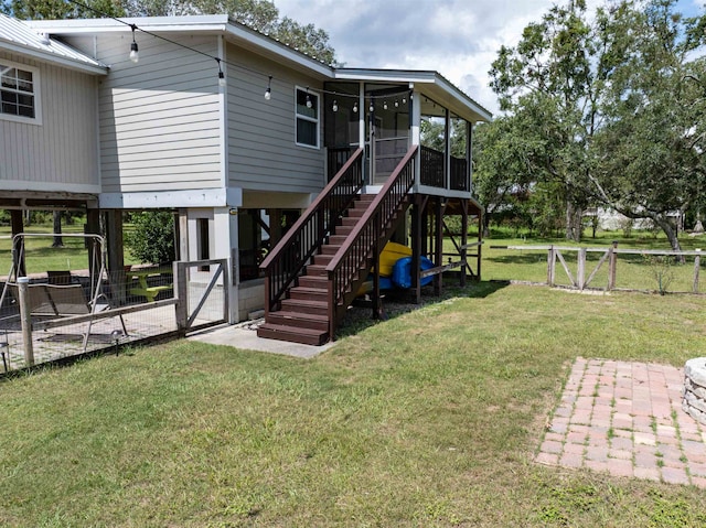 back of house with a lawn, a sunroom, and a patio area