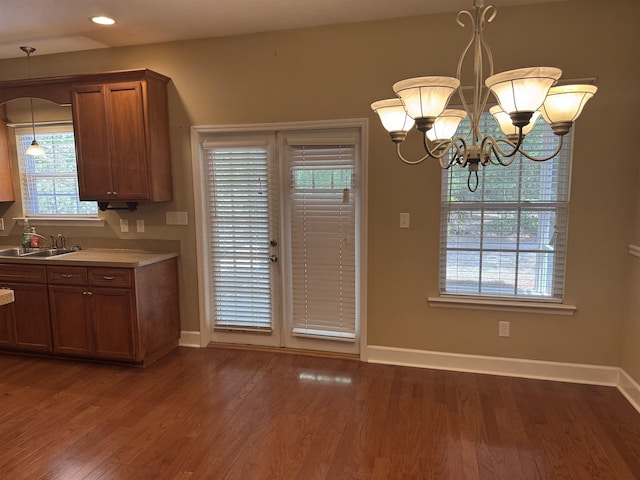 kitchen with dark wood-style flooring, baseboards, brown cabinetry, and a sink