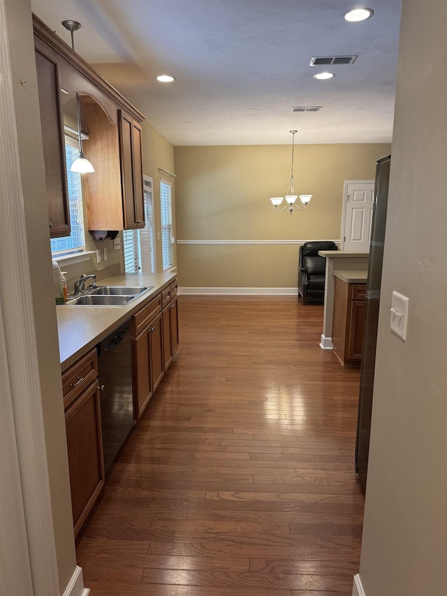 kitchen featuring visible vents, decorative light fixtures, dishwasher, a sink, and dark wood-type flooring
