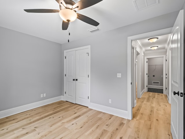 unfurnished bedroom with ceiling fan, a closet, ornamental molding, and light hardwood / wood-style flooring