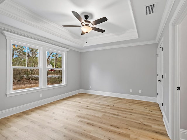 spare room with light wood-type flooring, a tray ceiling, ceiling fan, and crown molding