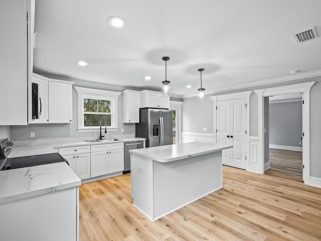 kitchen featuring a center island, sink, hanging light fixtures, stainless steel appliances, and light hardwood / wood-style flooring