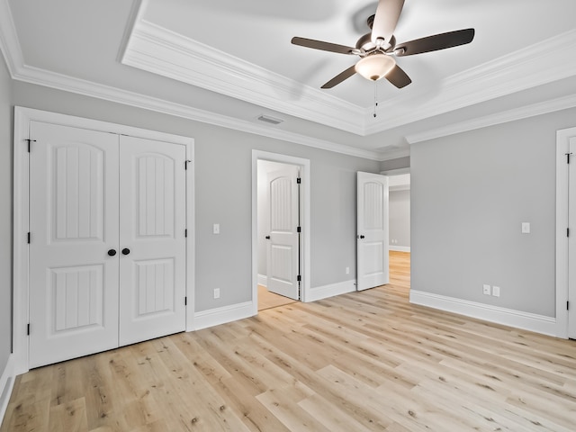 unfurnished bedroom with light hardwood / wood-style floors, a raised ceiling, ceiling fan, and ornamental molding