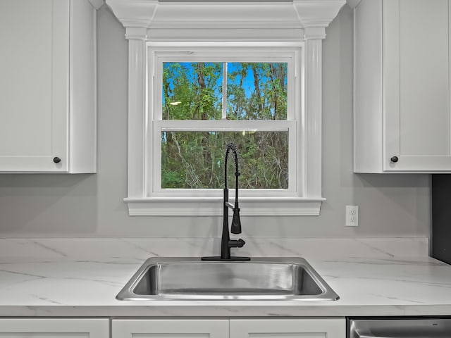 kitchen featuring dishwasher, white cabinetry, light stone countertops, and sink