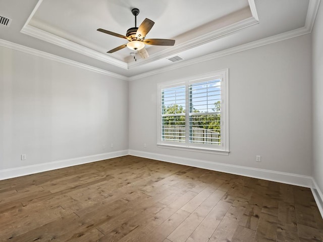 unfurnished room with wood-type flooring, a raised ceiling, and crown molding