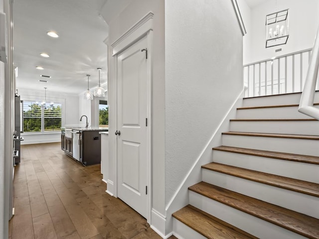 staircase featuring hardwood / wood-style flooring, a notable chandelier, and sink