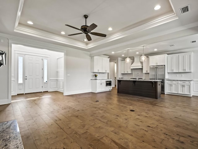 unfurnished living room with dark hardwood / wood-style flooring, a raised ceiling, ceiling fan, crown molding, and sink