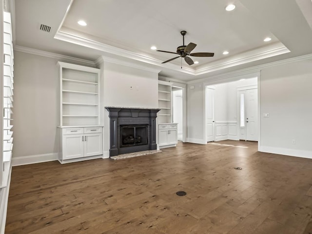 unfurnished living room with a raised ceiling, ceiling fan, dark wood-type flooring, and ornamental molding