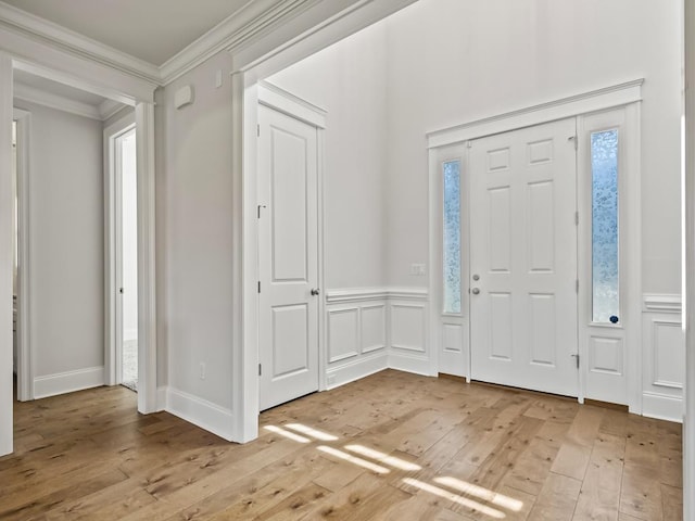 entryway featuring a healthy amount of sunlight, ornamental molding, and light hardwood / wood-style flooring