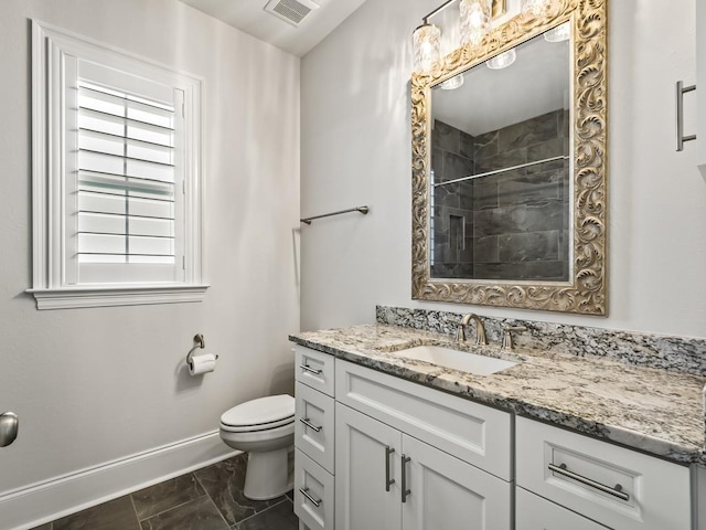 bathroom featuring tiled shower, vanity, and toilet