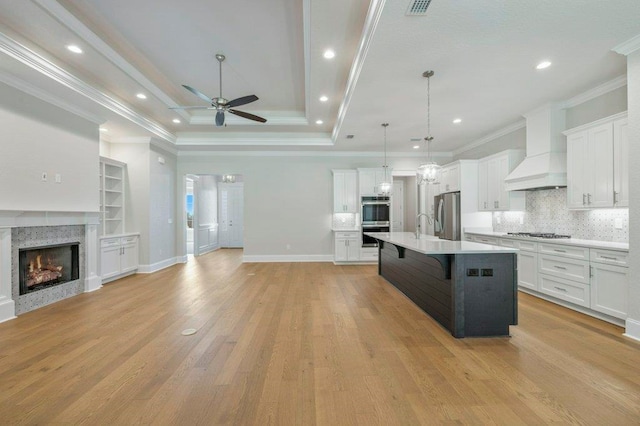 8451 Hickory Branch Trl, Tallahassee, FL 32312 - kitchen with appliances with stainless steel finishes, open floor plan, premium range hood, a ceiling fan, and a kitchen breakfast bar