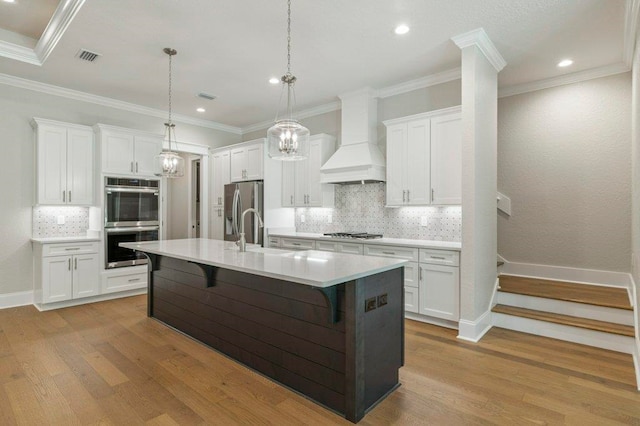 8451 Hickory Branch Trl, Tallahassee, FL 32312 - kitchen featuring appliances with stainless steel finishes, premium range hood, wood finished floors, backsplash, and white cabinets