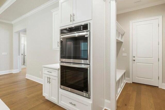 8451 Hickory Branch Trl, Tallahassee, FL 32312 - kitchen with stainless steel double oven, ornamental molding, light wood finished floors, and white cabinets
