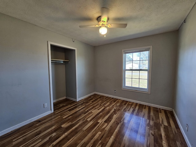 unfurnished bedroom featuring ceiling fan, a textured ceiling, dark hardwood / wood-style floors, and a closet