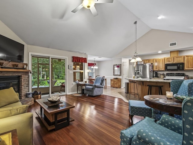 living room featuring ceiling fan, sink, dark hardwood / wood-style flooring, high vaulted ceiling, and a fireplace