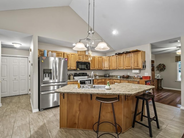 kitchen with sink, ceiling fan, an island with sink, decorative light fixtures, and stainless steel appliances