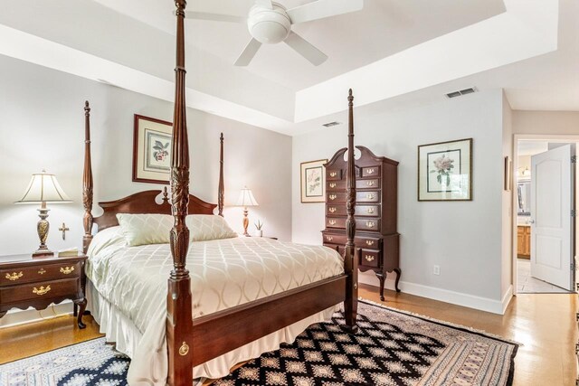3540 Trillium Ct, Tallahassee, FL 32312 - bedroom featuring a raised ceiling, wood finished floors, connected bathroom, and ceiling fan