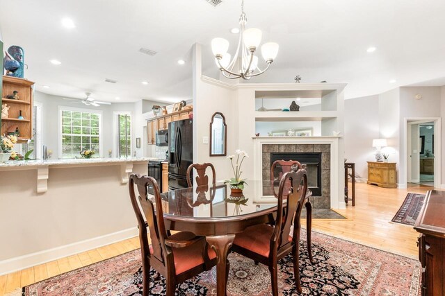 3540 Trillium Ct, Tallahassee, FL 32312 - dining space featuring light wood finished floors, recessed lighting, a chandelier, a tiled fireplace, and a ceiling fan