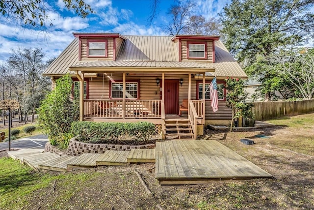 view of front of home featuring covered porch, metal roof, fence, and faux log siding