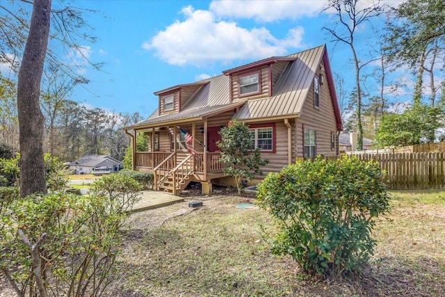 log cabin with a porch, metal roof, log exterior, fence, and a front lawn