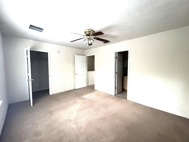 unfurnished bedroom featuring ceiling fan, a closet, light carpet, and ensuite bath