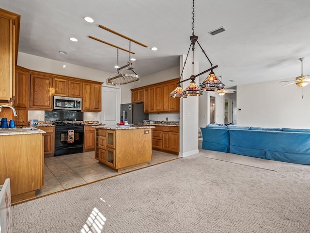 kitchen featuring light carpet, decorative light fixtures, appliances with stainless steel finishes, and a kitchen island