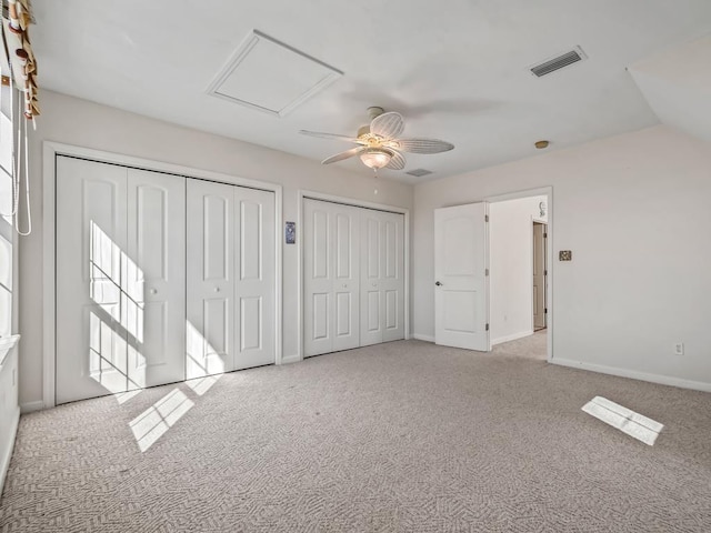 unfurnished bedroom with two closets, light colored carpet, and ceiling fan