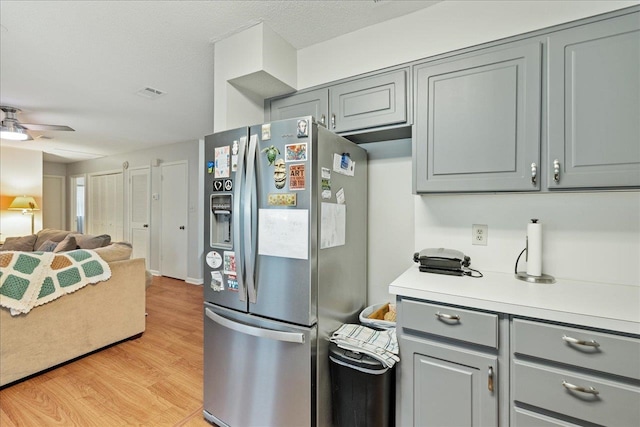 kitchen with stainless steel refrigerator with ice dispenser, a textured ceiling, gray cabinets, ceiling fan, and light wood-type flooring