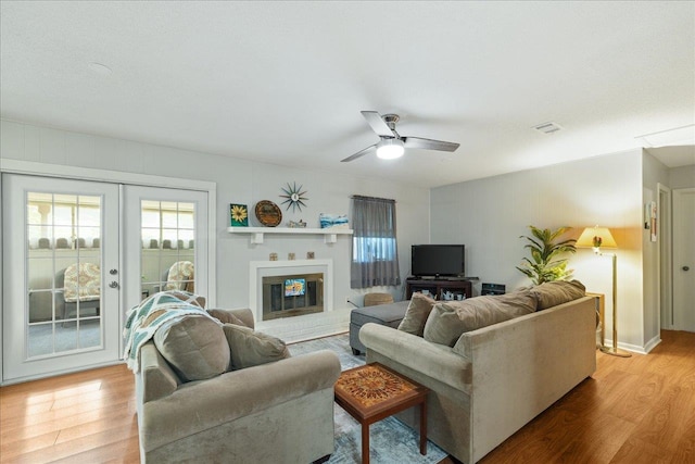 living room featuring ceiling fan, light wood-type flooring, and french doors