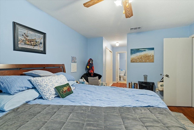 bedroom featuring hardwood / wood-style flooring, a textured ceiling, ceiling fan, and connected bathroom