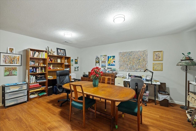 dining space with hardwood / wood-style floors and a textured ceiling