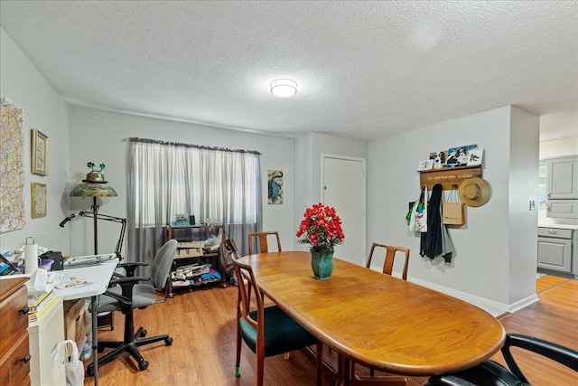 dining space with light hardwood / wood-style floors and a textured ceiling