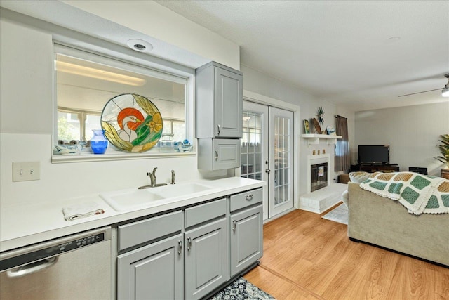 kitchen featuring dishwasher, sink, gray cabinetry, ceiling fan, and light wood-type flooring